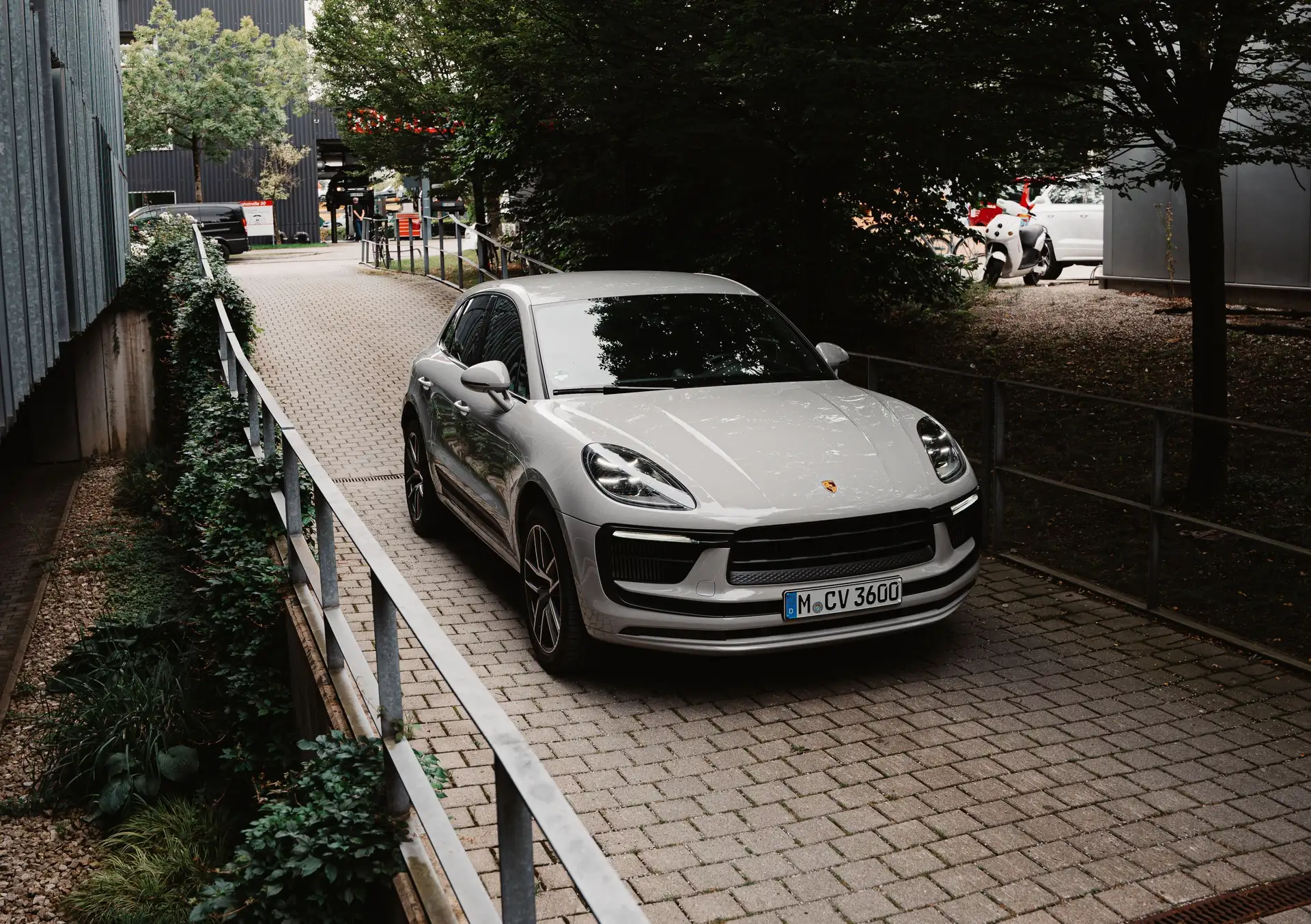 Ein Hero-Bild unseres Porsche Macan S in der Frontansicht aus etwas Distanz im Grünen. 
